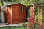 English back garden with potting shed and arch covered in Clematis