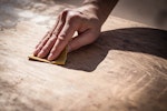 A woodworker sands down a wooden table