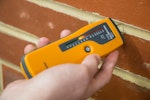 A protimeter being used to test the amount of moisture in the wall