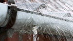 Rain pouring down on tiled roof with leaking gutter