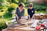 A Mother and Son build a wooden project in the garden.